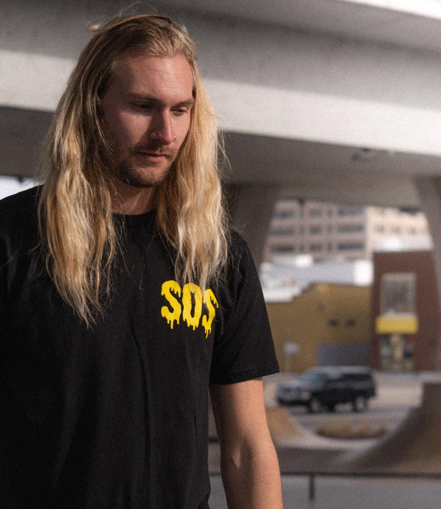 Model wearing a black SOS shirt with a yellow logo